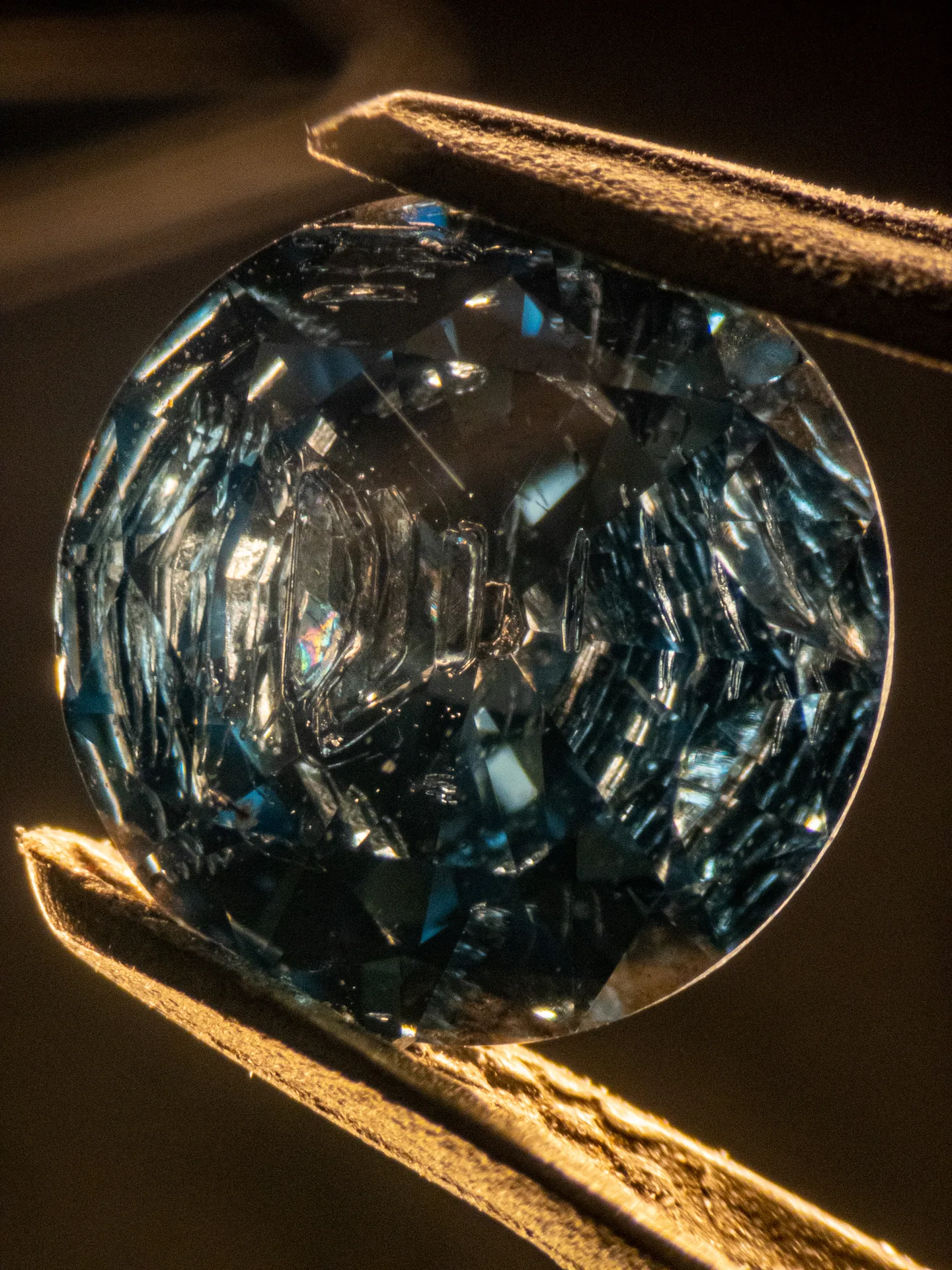 Blauer synthetischer HPHT-Diamant (Typ IIb, bordotiert) in der Pinzette, Dunkelfeld